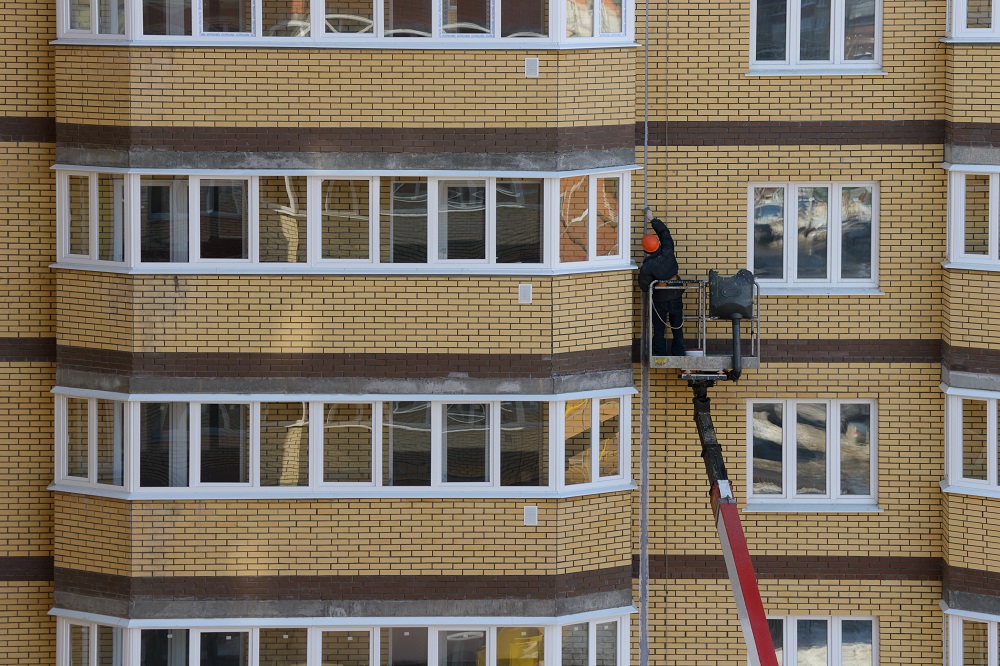 worker on an autotower repairs the facade of an apartment brick