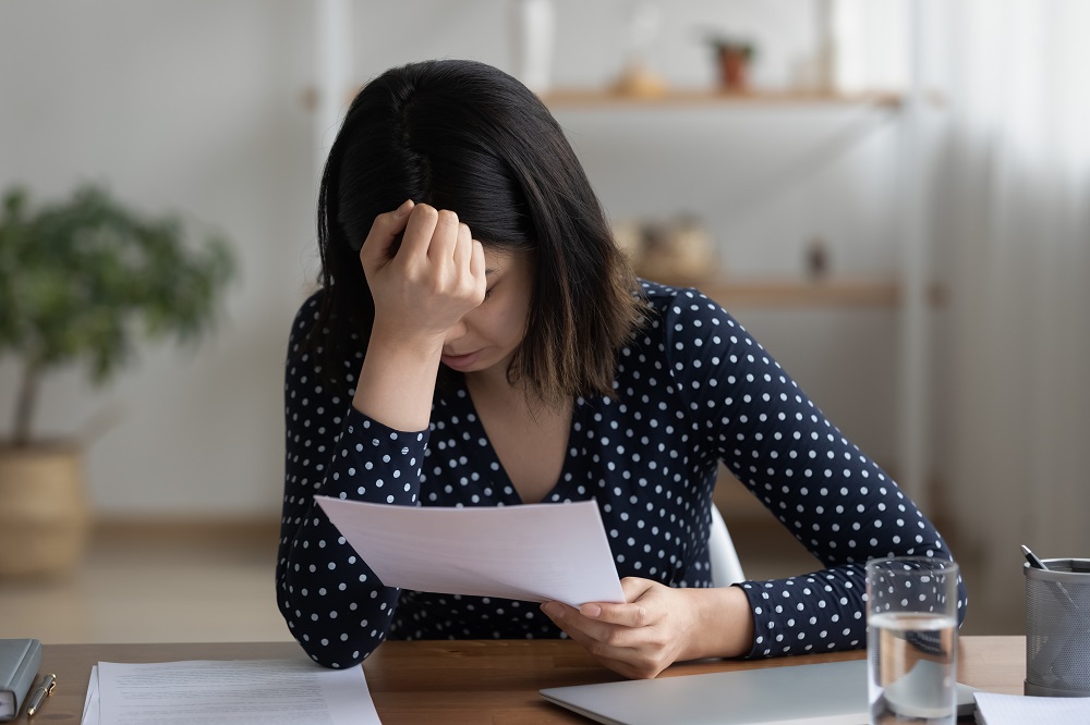 Close up frustrated Asian woman reading bad news in letter