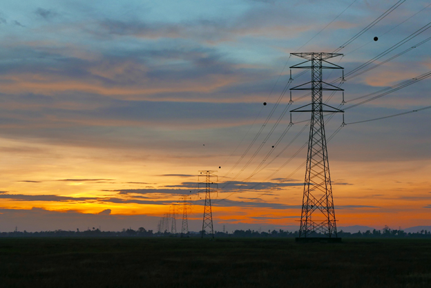 Sunset over electricity pylon on a paddy field at a village.