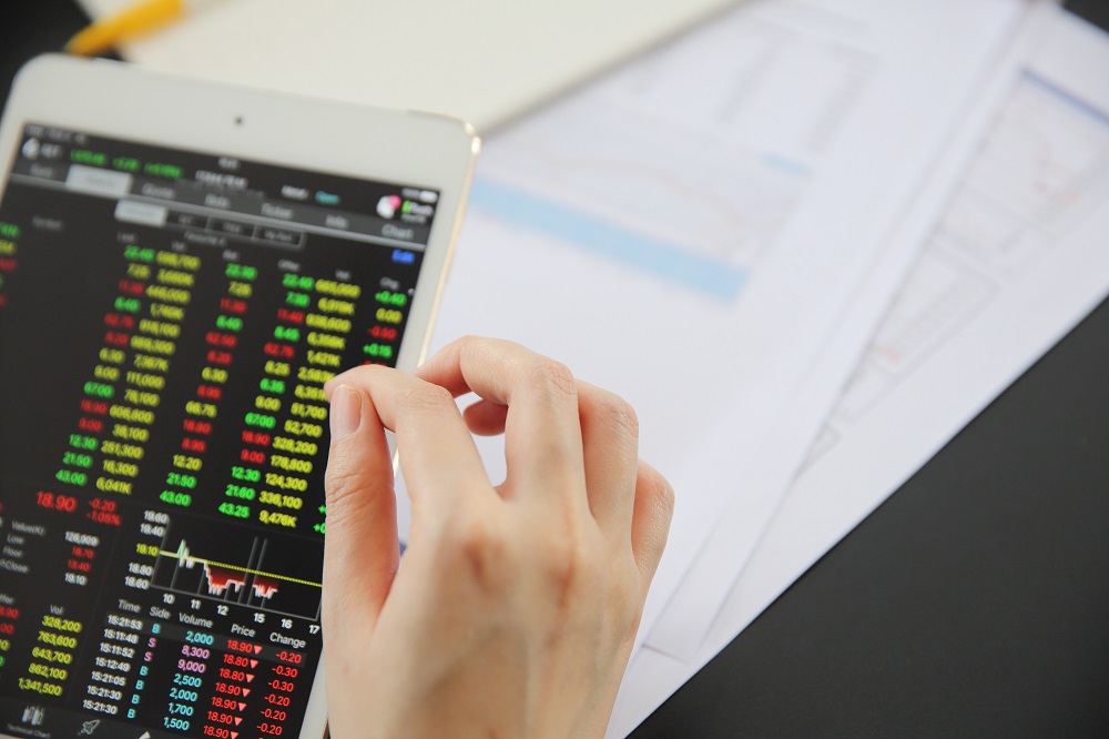 Woman hand Trading online on tablet with business paper and coff