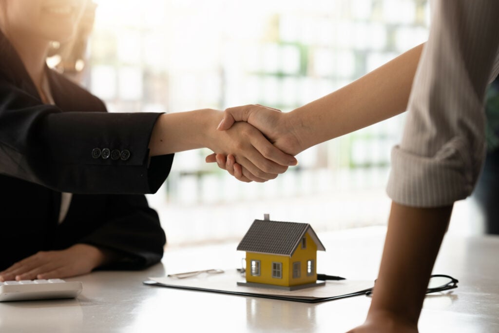 Real estate broker and customer shaking hands after signing a contract: real estate, home loan and insurance concept