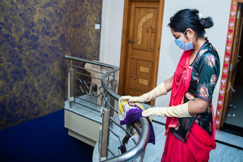 Coronavirus. Indian woman with face mask cleaning and disinfecting her house during coronavirus epidemic. cleaning metal railing. Prevention of COVID-19 infection. Stop coronavirus from spreading.