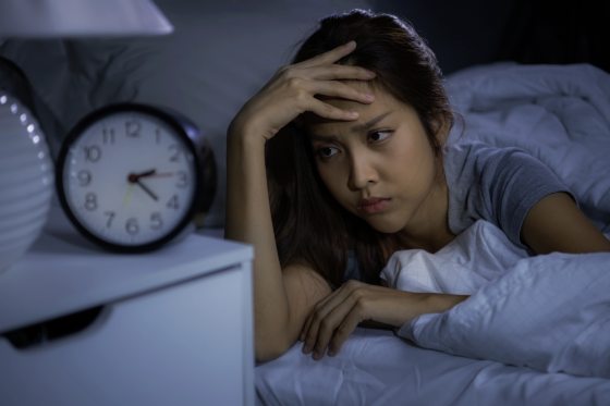 Depressed young woman lying in bed cannot sleep from insomnia