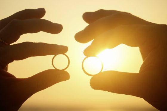 Two wedding rings on coral in front of the seaside at sunset