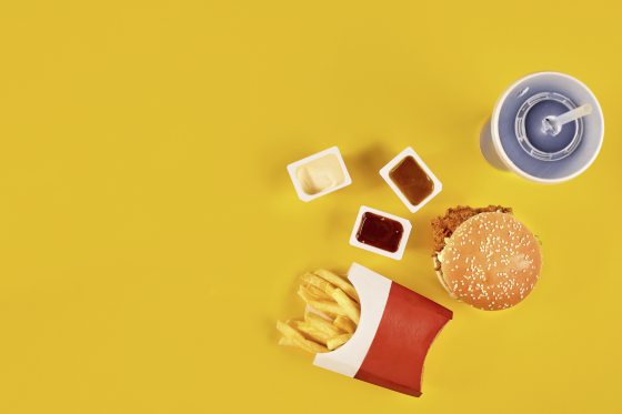 Fast food dish top view. Meat burger, potato chips and wedges. Take away composition. French fries, hamburger, mayonnaise and ketchup sauces on yellow background.