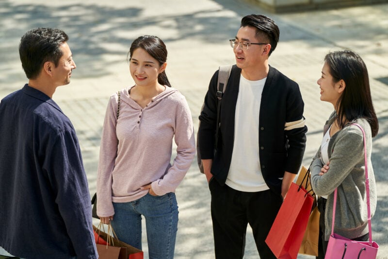 Young Asian Adult Men And Women With Shopping Bags Standing Talk