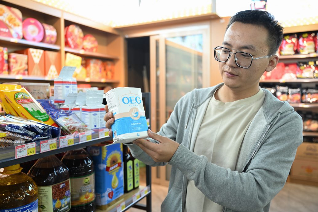 A shop owner displays a Mongolian flour product at an import supermarket in Erenhot, north China