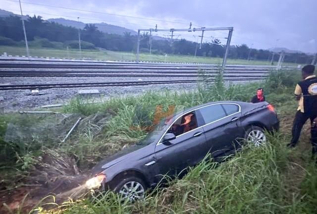 豪车雨中失控，轿车撞火车轨篱笆坠草丛