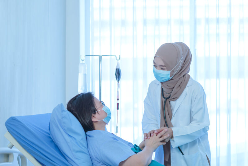 Muslim Female Doctor Holding Hand Of The Elderly Patient Sitting